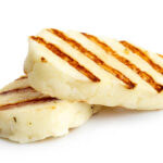 Two grilled slices of halloumi cheese isolated on white in perspective. With grill marks.